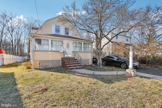 dutch colonial with a gambrel roof, entry steps, a front lawn, and fence