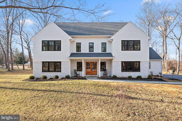 modern farmhouse with french doors, brick siding, board and batten siding, and a front yard