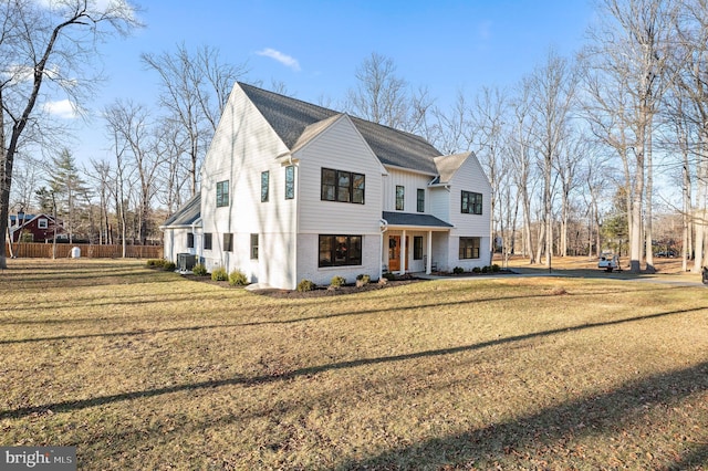 modern inspired farmhouse with brick siding, a front lawn, and fence