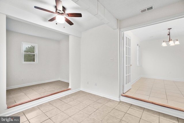 tiled spare room featuring visible vents, baseboards, and ceiling fan with notable chandelier