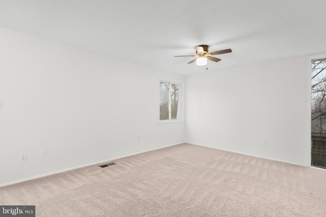 spare room featuring a ceiling fan, carpet, a healthy amount of sunlight, and visible vents