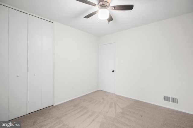 unfurnished bedroom featuring carpet floors, visible vents, baseboards, a ceiling fan, and a closet