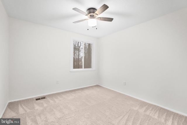 carpeted spare room with ceiling fan, visible vents, and baseboards