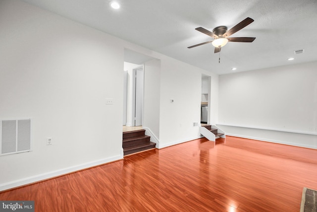 unfurnished living room with visible vents, stairway, baseboards, and wood finished floors