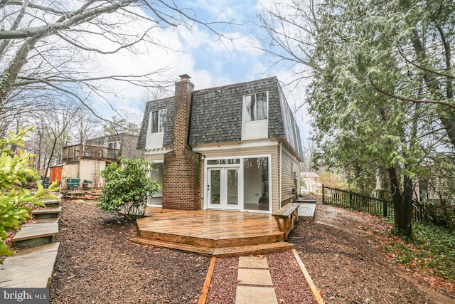 back of house with french doors, mansard roof, a shingled roof, fence, and a deck