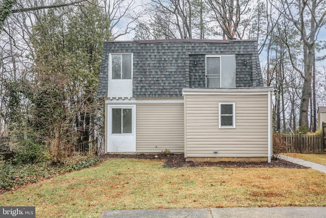 back of property with a shingled roof, fence, mansard roof, and a yard