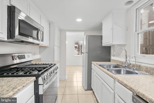 kitchen featuring light tile patterned floors, stainless steel appliances, light countertops, white cabinetry, and a sink