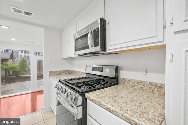 kitchen with appliances with stainless steel finishes, light tile patterned flooring, visible vents, and white cabinetry