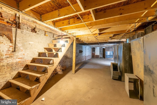 unfinished basement with brick wall and stairway