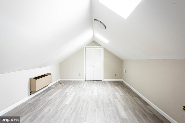 additional living space featuring lofted ceiling, baseboards, wood finished floors, and heating unit