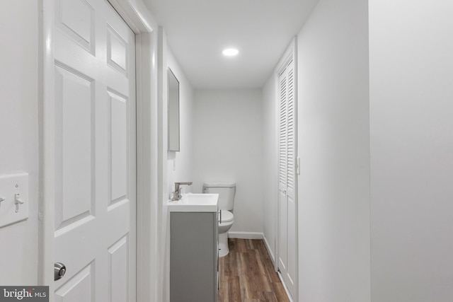 bathroom with baseboards, vanity, toilet, and wood finished floors