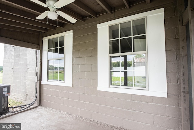 view of side of property with concrete block siding, ceiling fan, and central AC unit