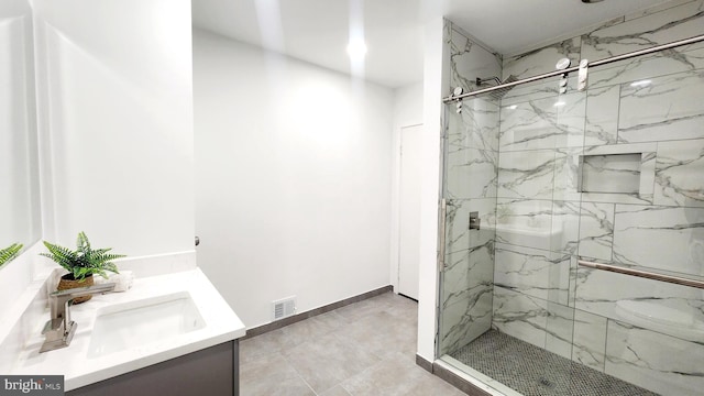 full bathroom featuring vanity, a marble finish shower, visible vents, and baseboards