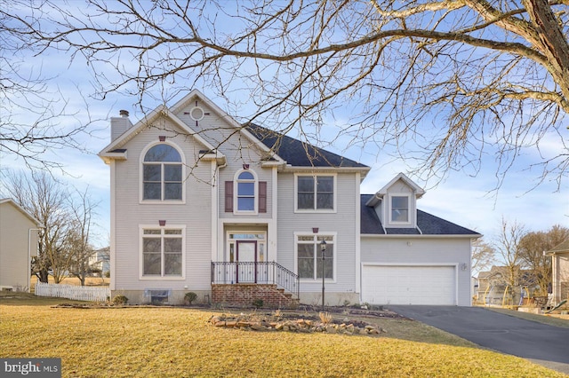 view of front of house featuring a garage, driveway, a chimney, and a front yard