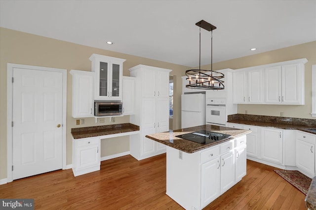 kitchen with white appliances, white cabinets, light wood-type flooring, a center island, and glass insert cabinets