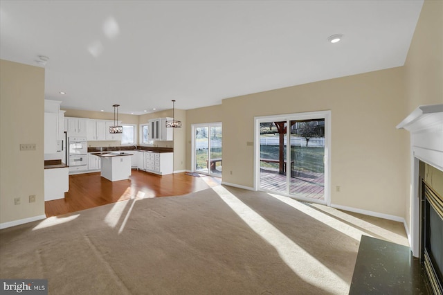 unfurnished living room featuring a glass covered fireplace, baseboards, and carpet