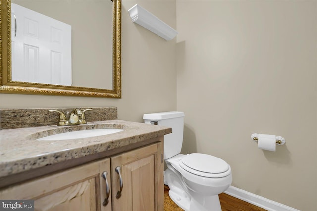 bathroom with toilet, baseboards, wood finished floors, and vanity