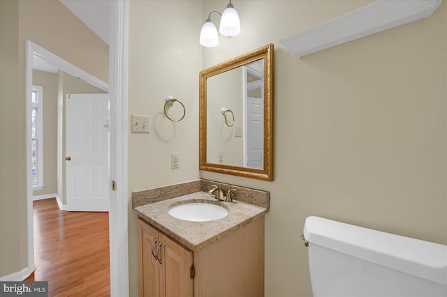 bathroom with toilet, baseboards, wood finished floors, and vanity