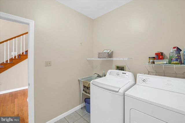 laundry area featuring laundry area, baseboards, washing machine and clothes dryer, and light tile patterned floors