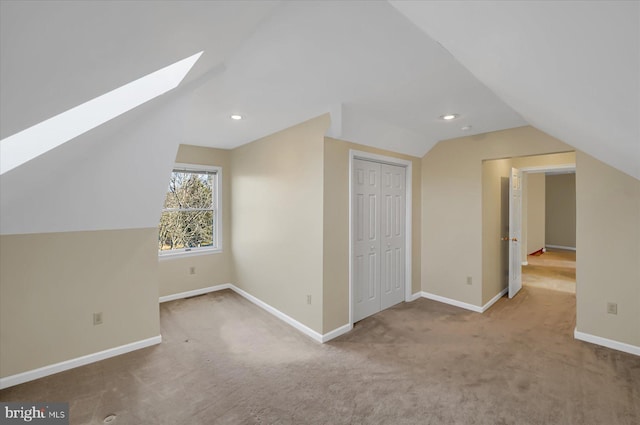 additional living space with vaulted ceiling with skylight, carpet, baseboards, and recessed lighting