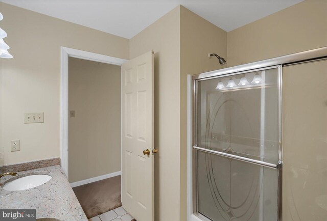 bathroom with a stall shower, baseboards, and vanity