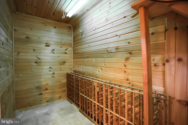 wine room with concrete flooring, a sauna, wooden ceiling, and wooden walls