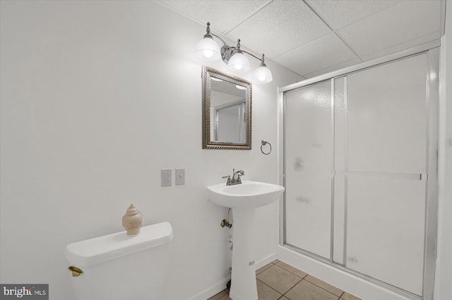 bathroom with a paneled ceiling, a stall shower, tile patterned flooring, and toilet