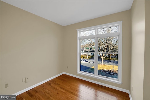 empty room featuring visible vents, baseboards, and wood finished floors