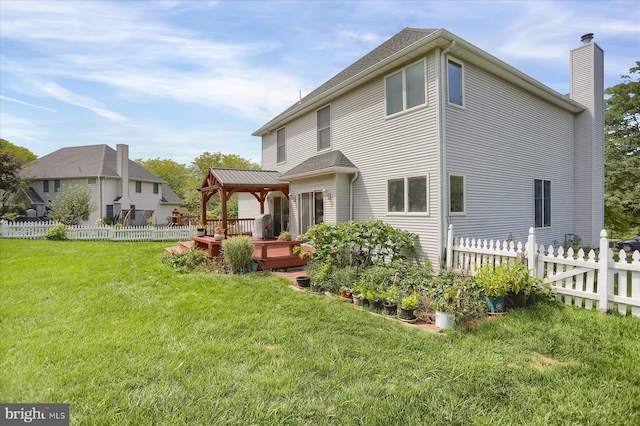 back of house featuring a yard, a chimney, fence, and a deck