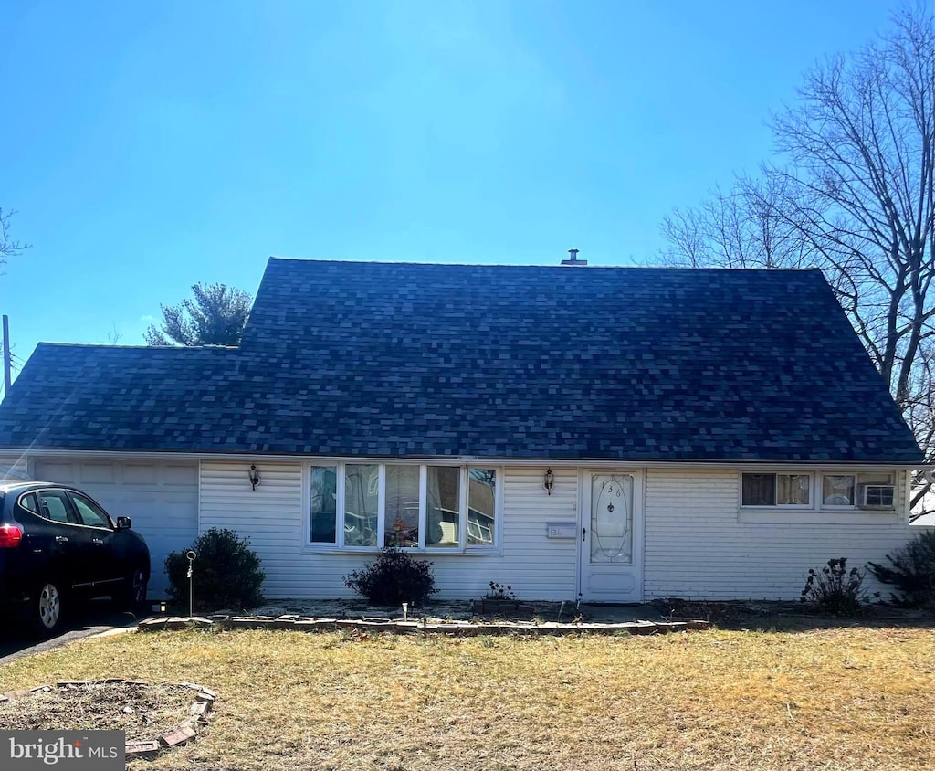 view of front of house featuring a garage, roof with shingles, and a front lawn