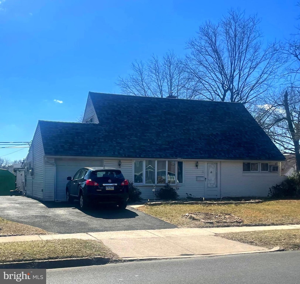 view of front of house with aphalt driveway, roof with shingles, and a garage