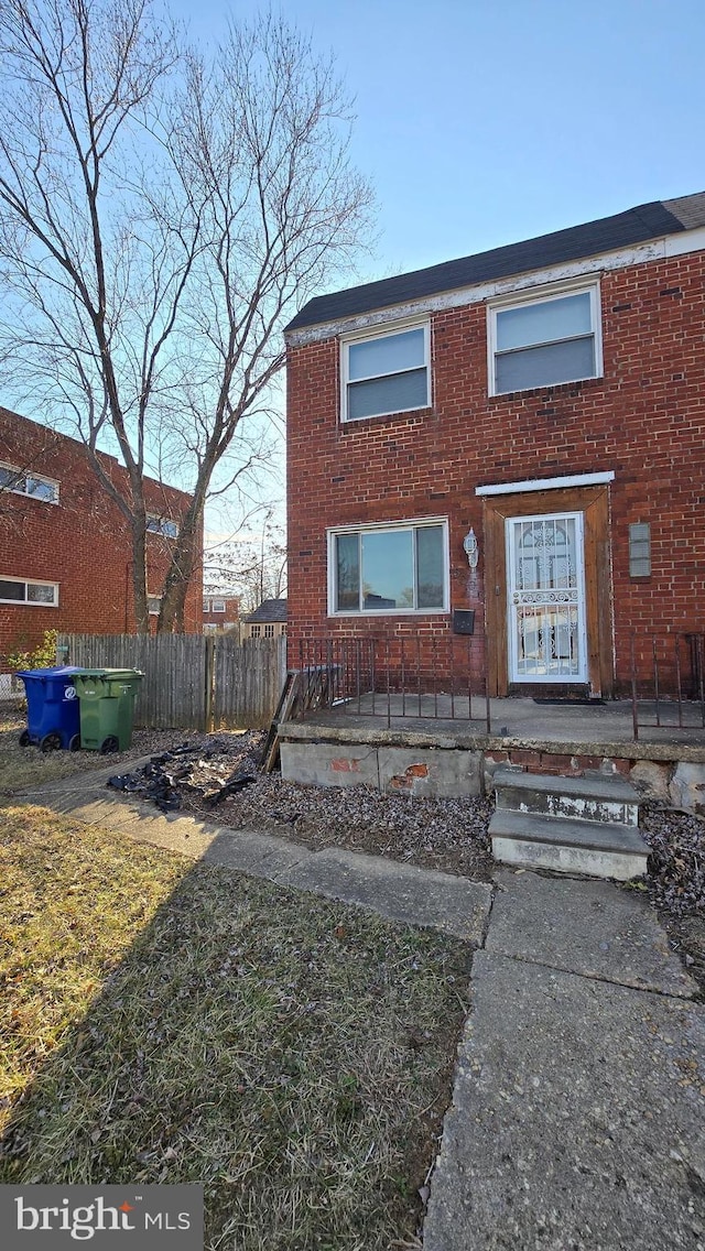 view of front facade with brick siding and fence