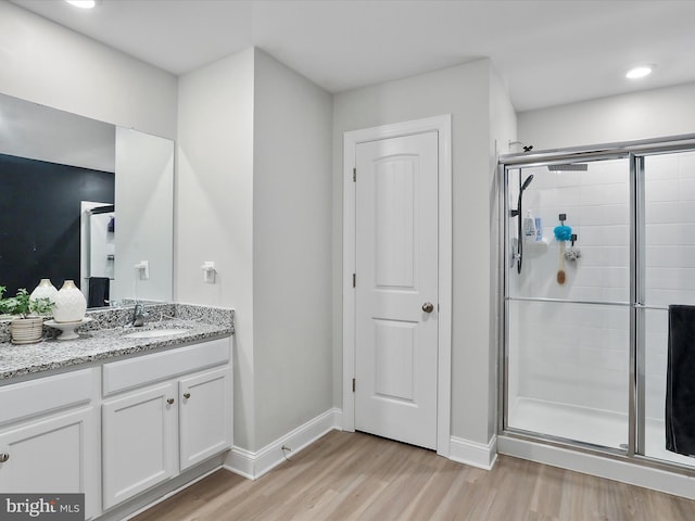 full bathroom with a stall shower, wood finished floors, recessed lighting, baseboards, and vanity