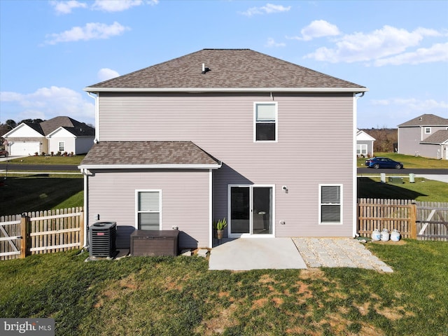 rear view of house with fence, roof with shingles, a yard, central AC, and a patio area