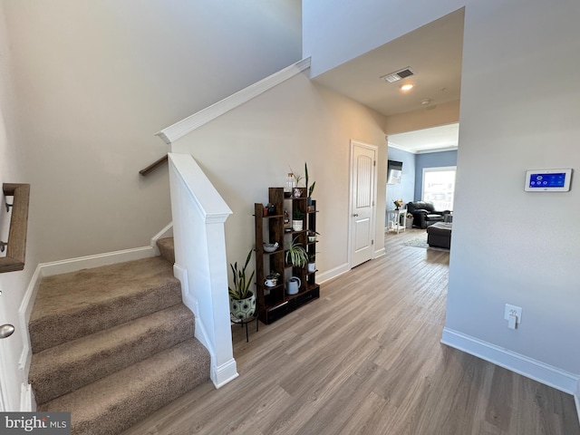 staircase with visible vents, baseboards, and wood finished floors