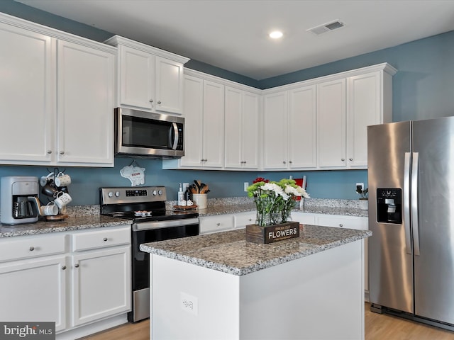 kitchen with visible vents, appliances with stainless steel finishes, white cabinets, light wood finished floors, and light stone countertops