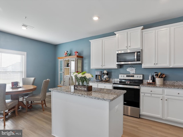 kitchen with visible vents, white cabinets, appliances with stainless steel finishes, light wood-type flooring, and a center island