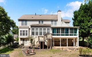 rear view of property with a sunroom, a patio area, a chimney, and stairs