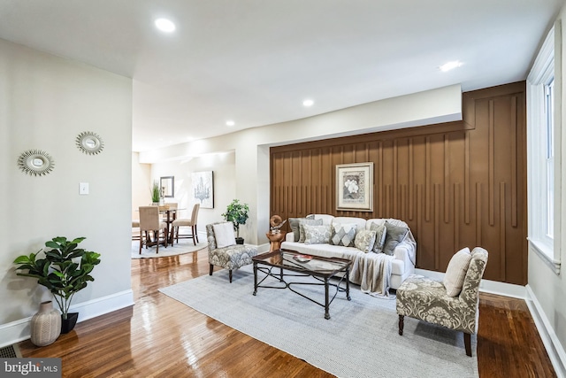 living area with baseboards, wood finished floors, and recessed lighting