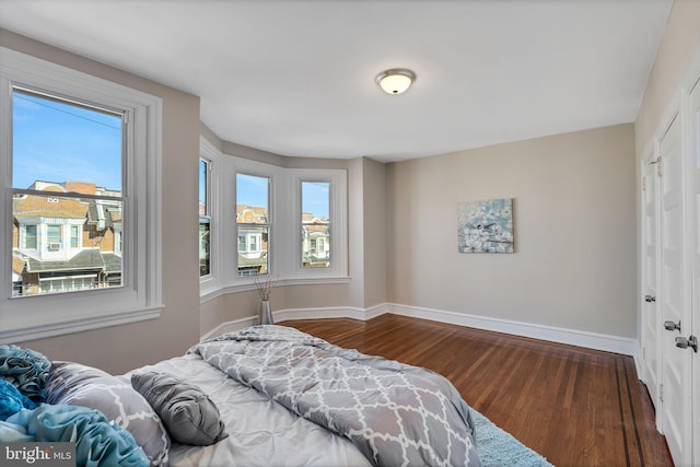 bedroom featuring multiple windows, baseboards, and wood finished floors