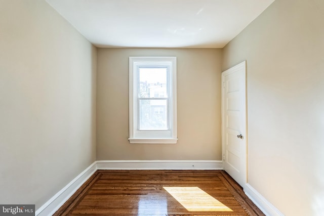 unfurnished room featuring baseboards and dark wood-style flooring