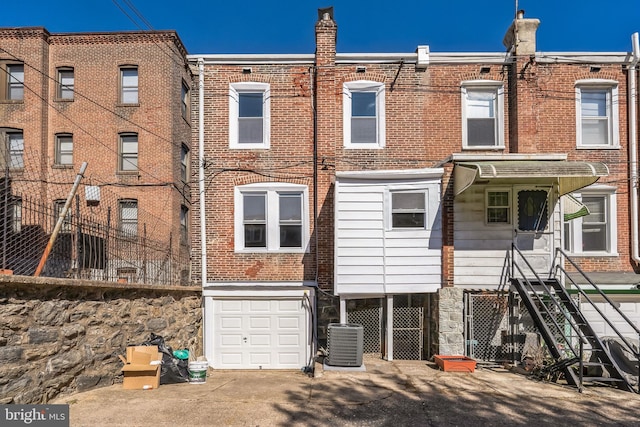 rear view of property featuring brick siding, an attached garage, and cooling unit