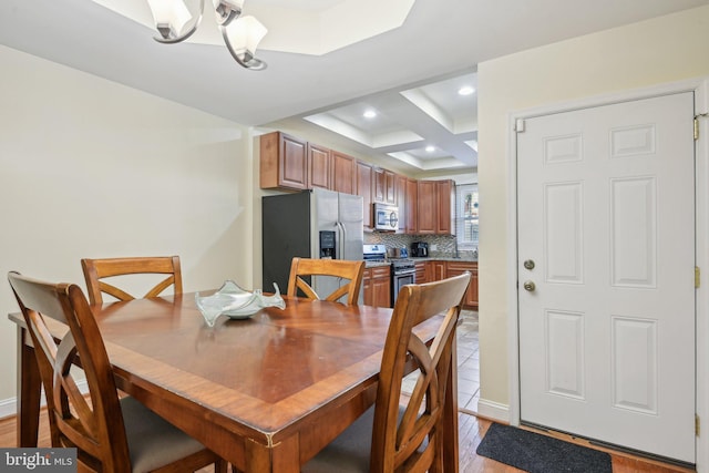 dining room featuring light wood-type flooring, beam ceiling, an inviting chandelier, coffered ceiling, and recessed lighting