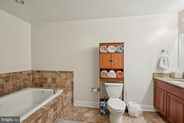 bathroom featuring vanity, toilet, a whirlpool tub, baseboards, and stone finish flooring