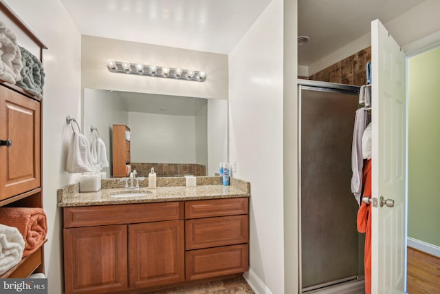 full bathroom with baseboards, a shower stall, and vanity