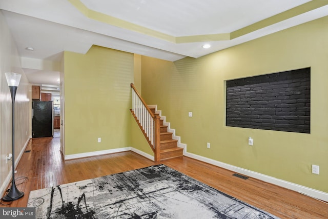 interior space featuring visible vents, baseboards, wood finished floors, and stairway