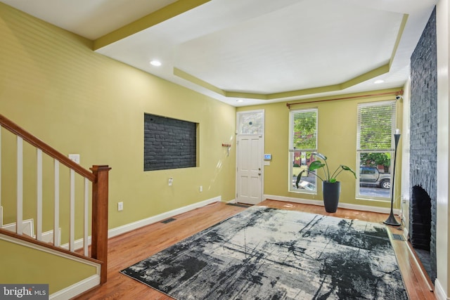entryway featuring a raised ceiling, stairs, baseboards, wood finished floors, and visible vents