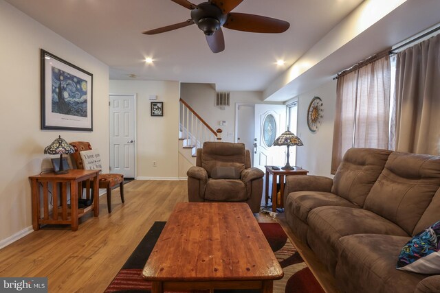 living area with light wood-style floors, visible vents, baseboards, and stairs