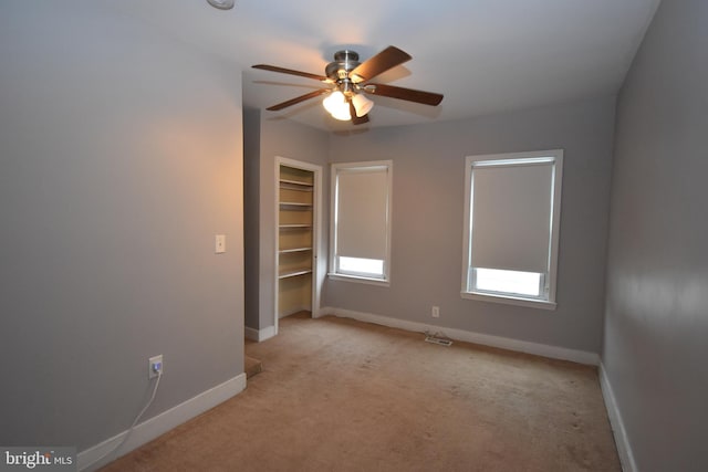 empty room featuring ceiling fan, light colored carpet, and baseboards