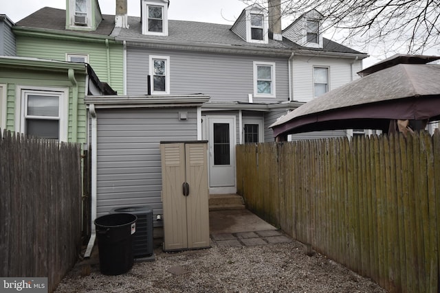 back of property with entry steps, central AC, and fence